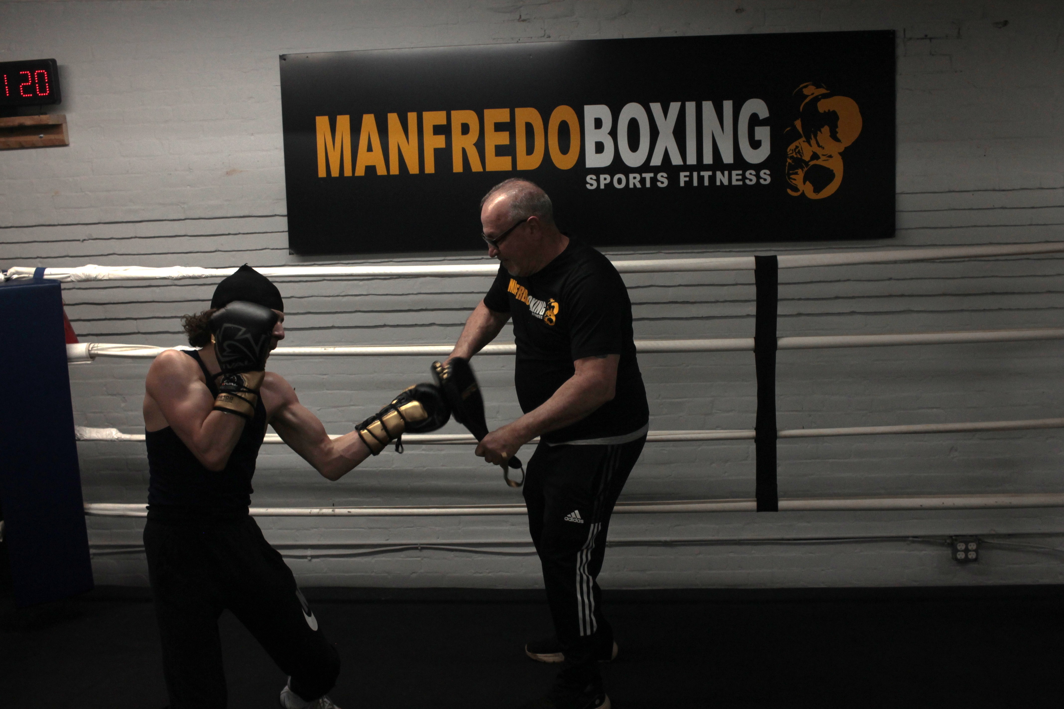 Peter Sr. holding mitts with fighter in the ring